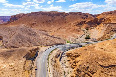  Asphalt highway meanders among the hills. Dead Sea mud has healing properties. Drone filming. Desert on the shores of the Dead Sea. Israel.