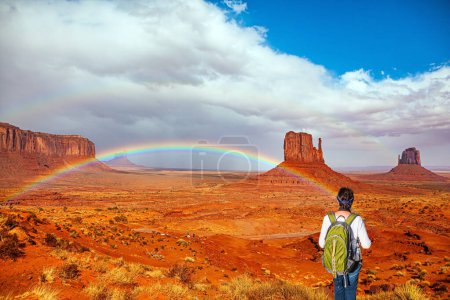 Mujer con una mochila verde. Monument Valley es una formación en Arizona y Utah. Estados Unidos. Reservas Indígenas Navajo. Uno de los símbolos nacionales de los Estados Unidos. El arco iris brillante