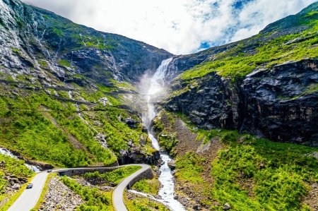 Téléchargez les photos : Trollstigen / Troll Staircase / - l'endroit touristique le plus populaire en Norvège. L'énorme cascade de Stigfossen. La route serpentine serpente pittoresque sur les pentes verdoyantes du canyon - en image libre de droit