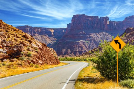 Breite Asphaltstraße zwischen malerischen Hügeln und Felsen von bizarren Formen. Die grandiosen Landschaften Amerikas. Utah Red Sandstones. Schöner Herbsttag