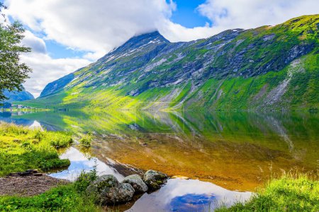 Téléchargez les photos : Lac profond avec de l'eau claire et transparente. L'eau reflète des nuages luxuriants, un ciel bleu et des rivages boisés. Eidsvatnet - majestueux lac en Norvège. L'été nordique en Scandinavie. - en image libre de droit