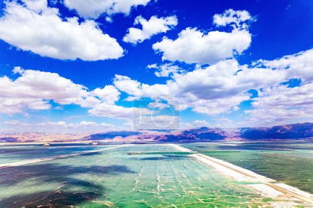  Israel. Das Tote Meer. Vogelperspektive. Wolkenschatten spiegeln sich im Wasser wider. Das verdunstete Salz wird auf dem Wasser gesammelt. Resort für Entspannung und Behandlung.
