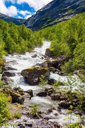 Norway. Rocky mountain stream flows among mountains. Wonderful fresh green vegetation and lush snow-white clouds. Travel to Scandinavia. Road to the Troll Staircase