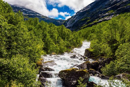 Norvège. Un ruisseau rocheux orageux coule entre les montagnes. Magnifique végétation verte fraîche et des nuages luxuriants blanc neige. Voyage en Scandinavie. Route vers l'escalier du Troll