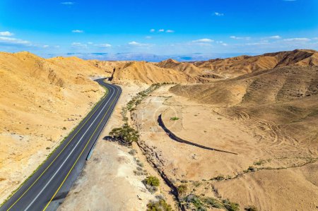 Desert on the shores of the Dead Sea. Dead Sea mud has healing properties. Asphalt highway meanders among the hills. Bird's eye view. Israel. 