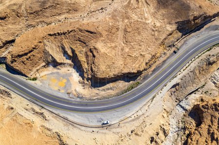Desert on the shores of the Dead Sea. Israel. Asphalt highway meanders among the hills. Dead Sea mud has healing properties. Bird's eye view.