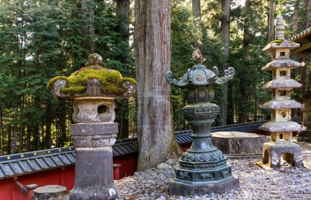 Puesta de sol. Las filas pares de faroles de piedra - esculturas. Japón. Nikko Tosho-gu es santuario sintoísta en Nikko. Construido en 1617. Majestuoso bosque de pinos y antiguo templo. 