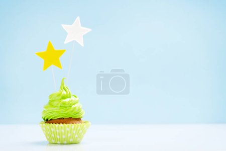Photo for Green cupcake with star decor on blue background with copy space - Royalty Free Image