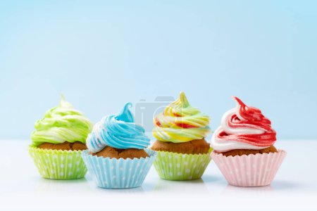 Téléchargez les photos : Cupcakes colorés sur fond bleu - en image libre de droit