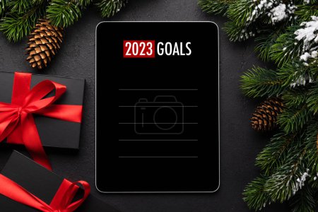 Téléchargez les photos : Tablette avec modèle de liste d'objectifs, boîtes-cadeaux et décor de Noël. Modèle d'écran de l'appareil de Noël - en image libre de droit