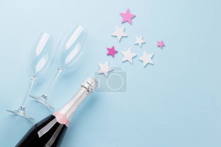Foto de Botella de champán y decoración de estrellas sobre fondo azul. Piso con espacio de copia - Imagen libre de derechos