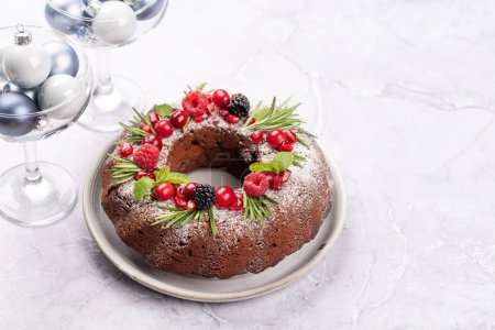 Téléchargez les photos : Gâteau de Noël décoré de graines de grenade, de canneberges et de romarin. Avec espace de copie - en image libre de droit