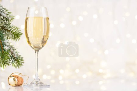 Téléchargez les photos : Verre à champagne devant les lumières de Noël bokeh avec espace de copie pour vos salutations de Noël - en image libre de droit