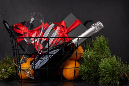 Foto de Cesta con cajas de regalo de Navidad, champán, naranjas y decoración - Imagen libre de derechos