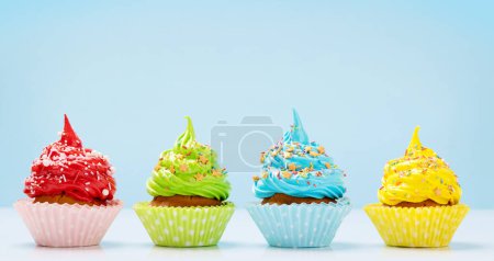 Téléchargez les photos : Cupcakes colorés sur fond bleu avec espace de copie - en image libre de droit
