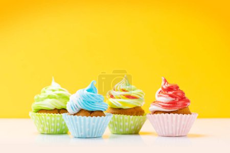 Foto de Coloridos cupcakes sobre fondo amarillo con espacio para copiar - Imagen libre de derechos
