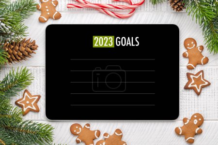 Téléchargez les photos : Tablette avec modèle de liste d'objectifs, biscuits au pain d'épice et décor de Noël. Modèle d'écran de l'appareil de Noël - en image libre de droit