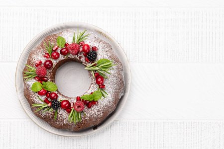Foto de Pastel de Navidad decorado con semillas de granada, arándanos y romero. Piso con espacio de copia - Imagen libre de derechos