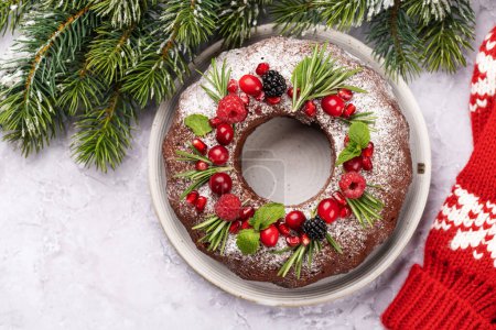 Photo for Christmas cake decorated with pomegranate seeds, cranberries and rosemary. Flat lay with copy space - Royalty Free Image