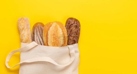 Photo for Fresh baked bread in bag on yellow background. Flat lay with copy space - Royalty Free Image
