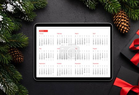 Photo for Tablet with calendar, gift boxes and Christmas decor. Xmas device screen template - Royalty Free Image