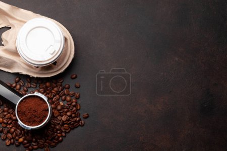 Téléchargez les photos : Café frais dans une tasse à emporter, grains de café torréfiés et café moulu dans le porte-filtre. Vue du dessus plat avec espace de copie - en image libre de droit