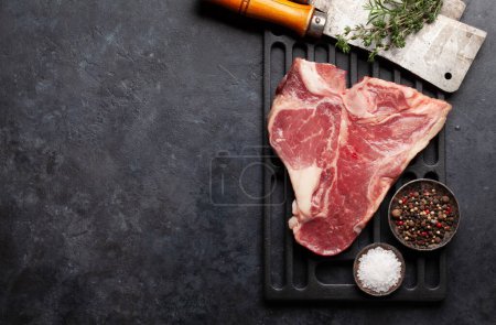 Photo for Porterhouse or T-bone raw beef steak with herbs and spices over grill. Top view flat lay with copy space - Royalty Free Image