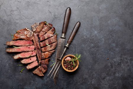 Photo for Grilled porterhouse beef steak. Sliced T-bone with herbs and spices. Top view flat lay with copy space - Royalty Free Image