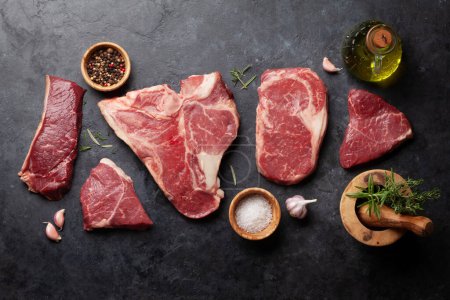 Photo for Various raw beef steaks with herbs and spices. Top view flat lay - Royalty Free Image