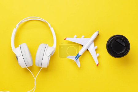 Téléchargez les photos : Concept de voyage et vacances. Écouteurs, café et avion sur bureau jaune - en image libre de droit