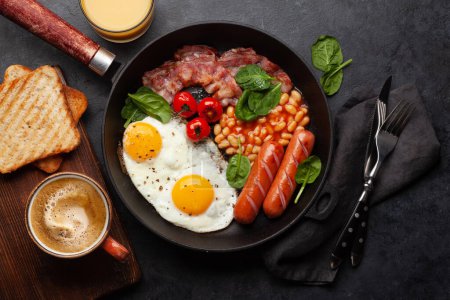 Foto de Desayuno inglés con huevos fritos, frijoles, tocino y salchichas. Vista superior plano con café y zumo de naranja - Imagen libre de derechos