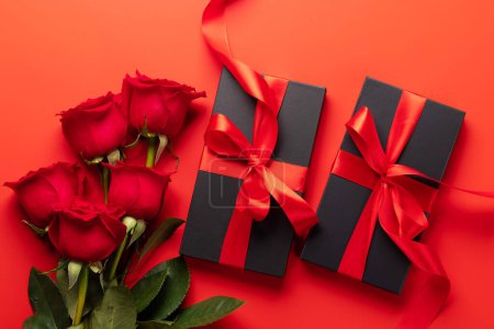 Foto de Tarjeta de San Valentín con cajas de regalo y flores rosadas. Sobre fondo rojo - Imagen libre de derechos