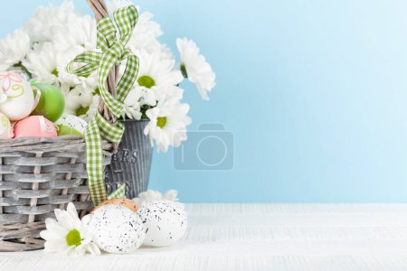 Foto de Tarjeta de felicitación de Pascua con huevos de Pascua y flores en cesta. Con espacio de copia - Imagen libre de derechos