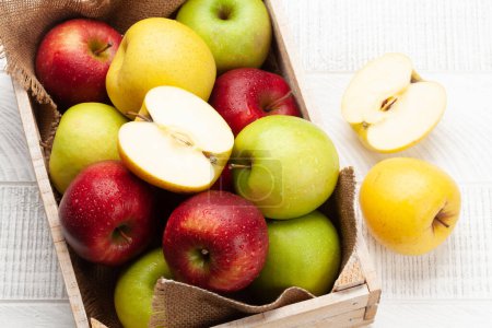 Foto de Coloridos frutos maduros de manzana en caja sobre mesa de madera. Vista superior - Imagen libre de derechos