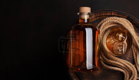 Téléchargez les photos : Bouteille avec rhum, cognac ou whisky. Sur un vieux tonneau de bois. Vue du dessus plat avec espace de copie - en image libre de droit