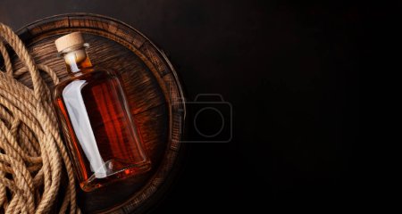 Photo for Bottle with rum, cognac or whiskey. Over old wooden barrel. Top view flat lay with copy space - Royalty Free Image