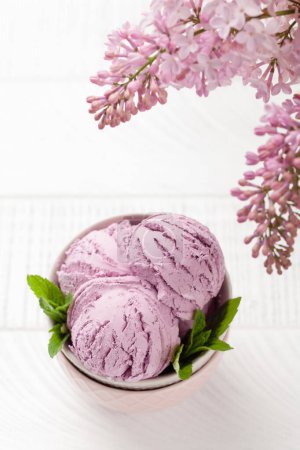Téléchargez les photos : Crème glacée aux baies sundae dans un bol et fleurs lilas. Avec espace de copie - en image libre de droit