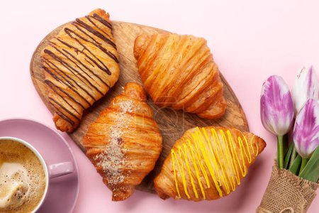 Photo for Various croissants and coffee on wooden board and tulip bouquet. French breakfast. Top view flat lay - Royalty Free Image