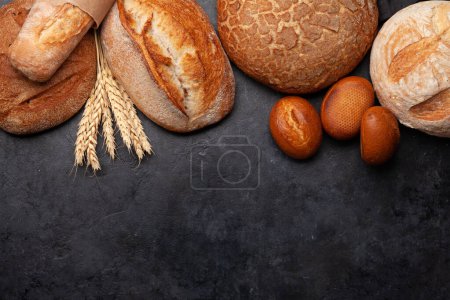 Foto de Varios tipos de pan en la mesa de piedra. Vista superior plano con espacio de copia - Imagen libre de derechos