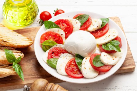 Téléchargez les photos : Salade de caprese avec mozzarella, basilic, tomates fraîches de jardin et pain grillé - en image libre de droit