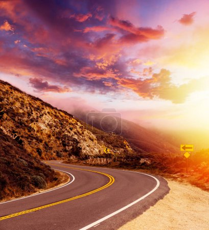 Foto de Camino de asfalto vacío en el paisaje rural al atardecer con cielo dramático - Imagen libre de derechos