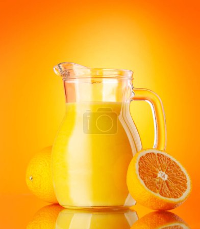 Téléchargez les photos : Jus d'orange frais dans un pichet en verre sur fond d'orange - en image libre de droit
