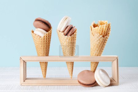 Photo for Various macaroon cookies in ice cream cones. On blue background - Royalty Free Image