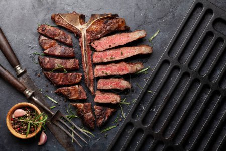 Téléchargez les photos : Steak de bœuf grillé à la porterhouse. T-bone tranché aux herbes et aux épices. Vue du dessus plat lay - en image libre de droit