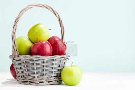 Foto de Coloridos frutos maduros de manzana en cesta sobre mesa de madera. Con espacio de copia - Imagen libre de derechos
