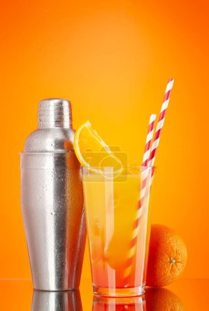 Foto de Cóctel coctelera y cóctel de salida del sol de tequila sobre fondo naranja con espacio para copiar - Imagen libre de derechos