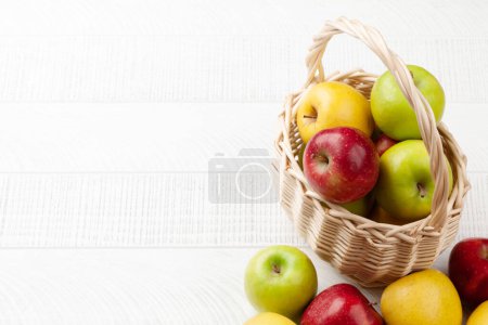 Téléchargez les photos : Fruits de pomme mûrs colorés dans le panier sur une table en bois. Avec espace de copie - en image libre de droit