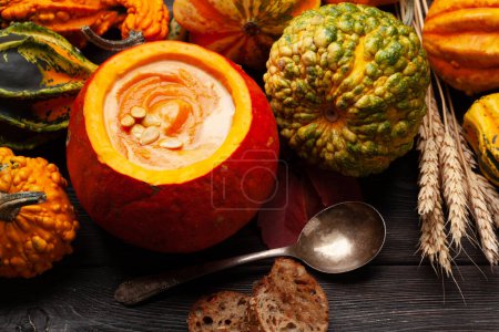 Foto de Sopa de crema de calabaza y varias calabazas y calabazas de colores. Cosecha de verduras de otoño. Vista superior - Imagen libre de derechos