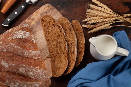 Téléchargez les photos : Trancher le pain fait maison et les ingrédients sur une table en bois. Pose plate - en image libre de droit