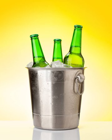 Foto de Botellas de cerveza en cubo de hielo. Sobre fondo amarillo - Imagen libre de derechos